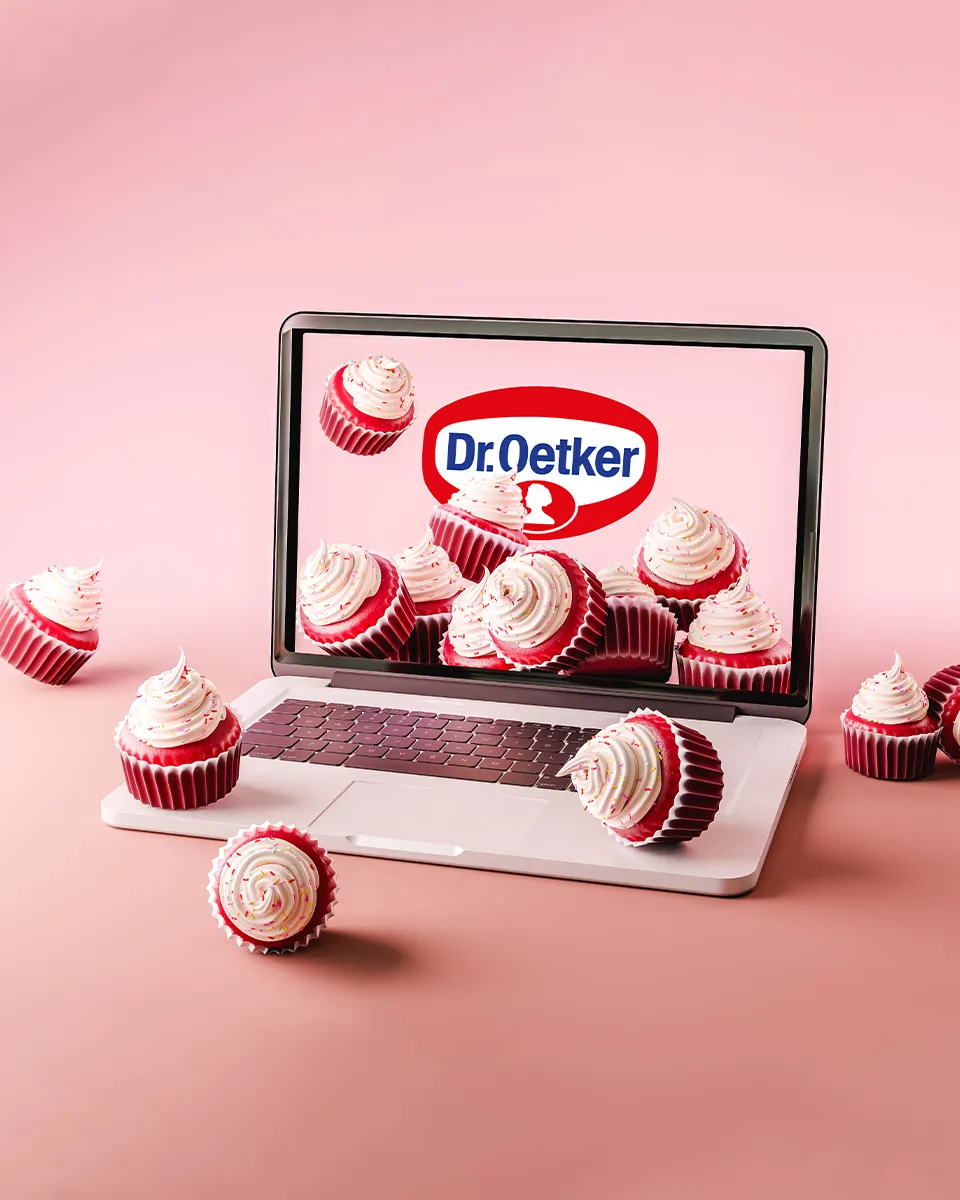 Na roze pozadini je postavljen laptop na čijem se ekranu vidi logo Dr. Oetker i nekoliko kolačića crveni baršun