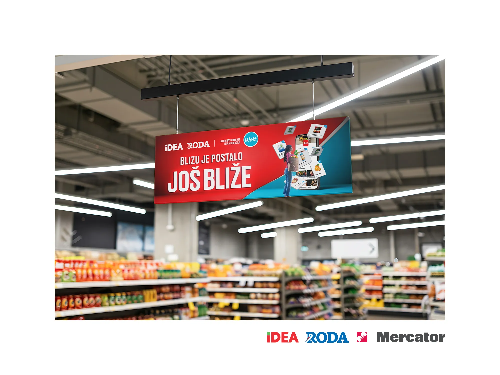 Unutrašnjost supermarketa sa visilicom na kojoj je kreativa za kampanju Wolt i Mercator saradnje Blizu je postalo još bliže